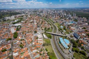 invest-sjc-empresas-multinacionais-sjc Vista aérea de São José dos Campos com áreas urbanas, vias de acesso e edifícios, representando o ambiente econômico que atrai empresas multinacionais.