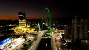 invest-sjc-exportacoes-sjc Vista aérea noturna da Ponte Estaiada de São José dos Campos iluminada em verde, símbolo da infraestrutura moderna e da força das exportações da cidade no cenário industrial brasileiro.
