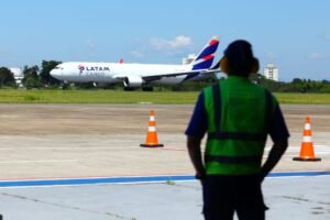 invest-sjc-fabrica-de-avioes Aeronave cargueira em aeroporto com profissional de operações em primeiro plano, representando a cadeia logística da indústria aeronáutica e fábricas de aviões no Brasil.
