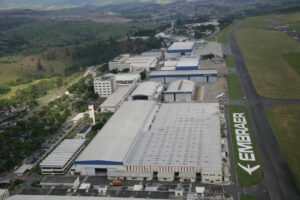 从空中俯瞰巴西航空工业公司的工业园区，可以看到机库和机场跑道，代表了巴西的技术基础设施和投资机会。