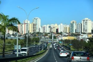 Veduta panoramica di un viale trafficato di São José dos Campos, circondato da edifici e aree verdi, che rappresenta l'economia di São José dos Campos, caratterizzata da innovazione, infrastrutture moderne, industria e sviluppo tecnologico.