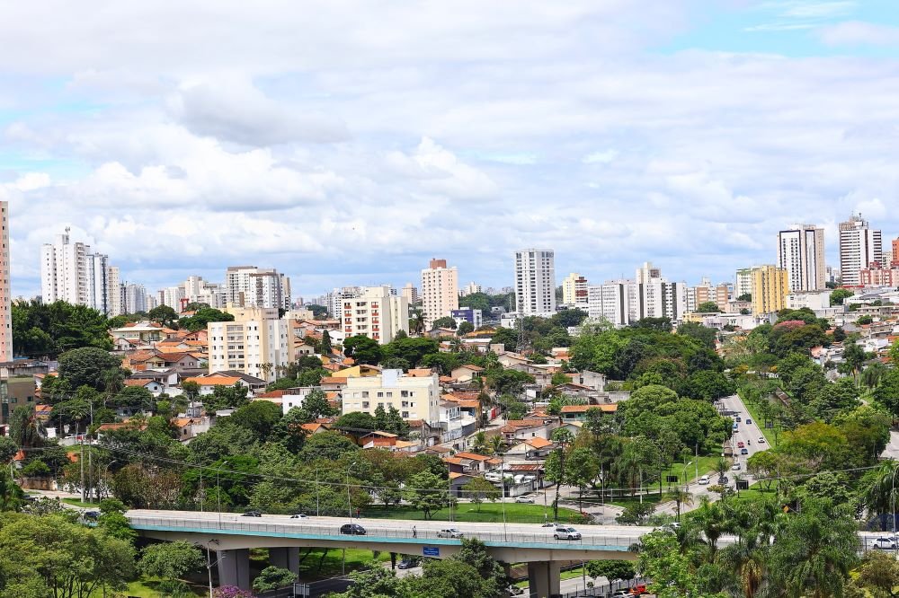 Panoramic view of an urban area with buildings, residential neighborhoods, green spaces, and an overpass, representing real estate investment in Brazil in a city with modern infrastructure, economic growth, and high potential for appreciation.
